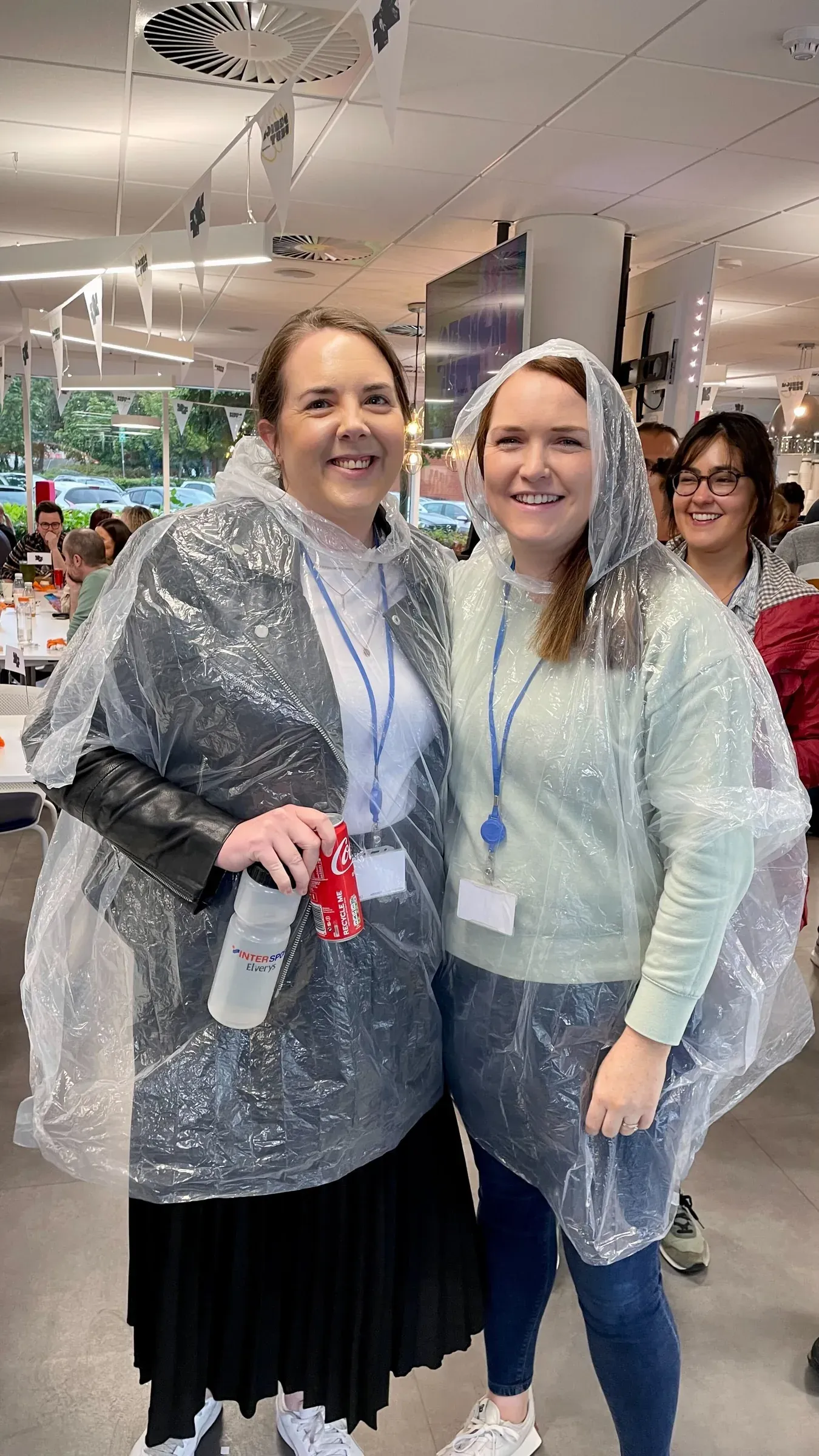 Two colleagues in rain ponchos, laughing