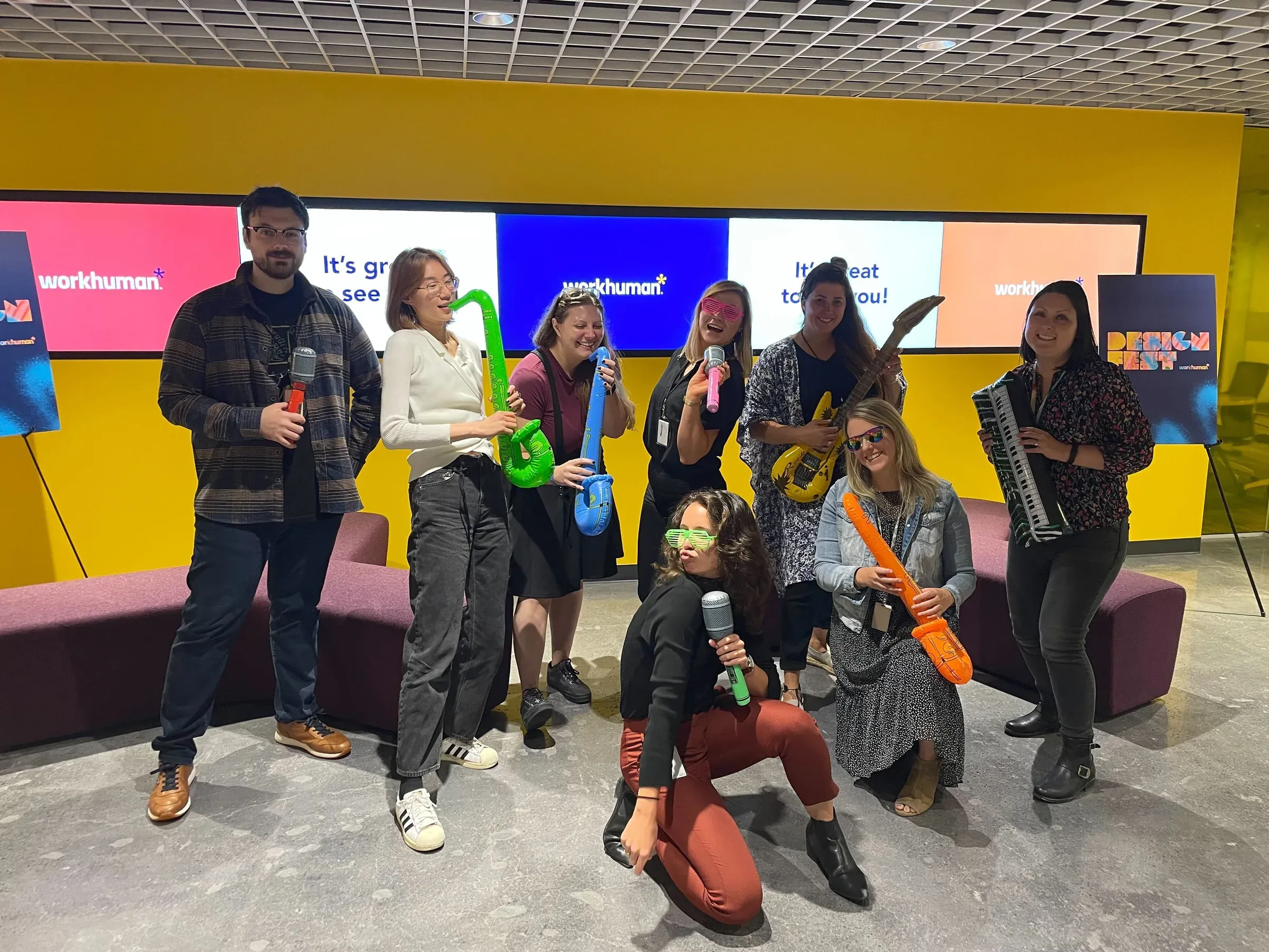 A team posing with inflatable instruments in front of Design Fest screens